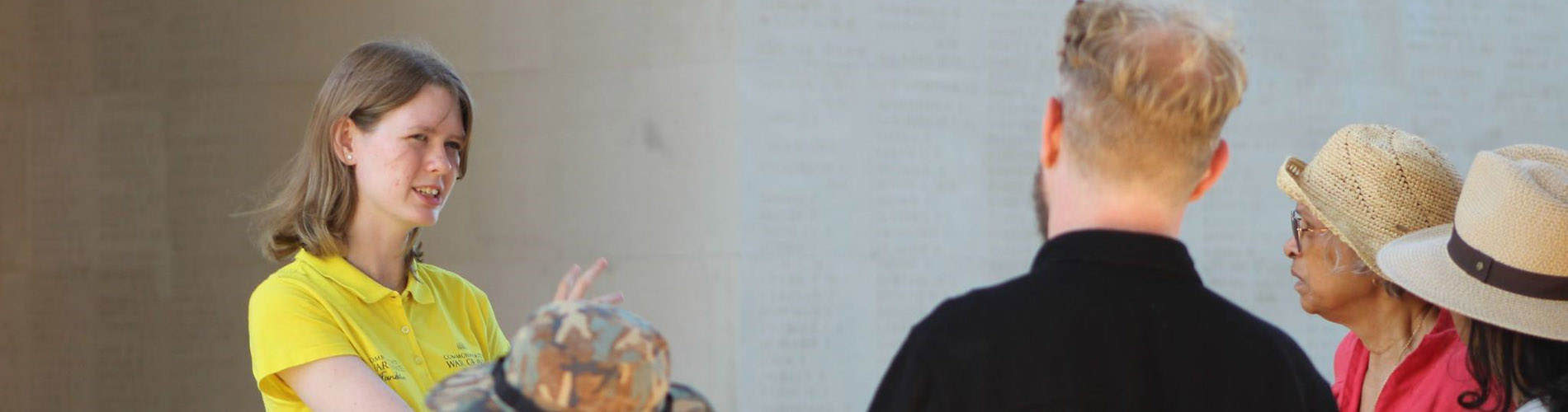 Person in front of a memorial talking to a group