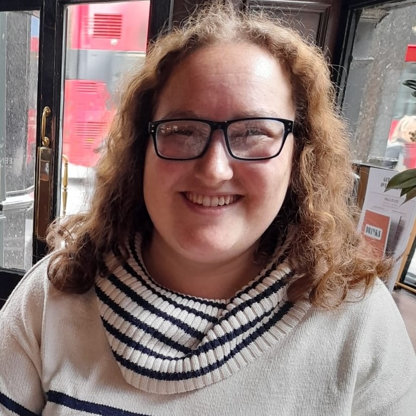 Ella Kirsch headshot wearing glasses with shoulder length hair