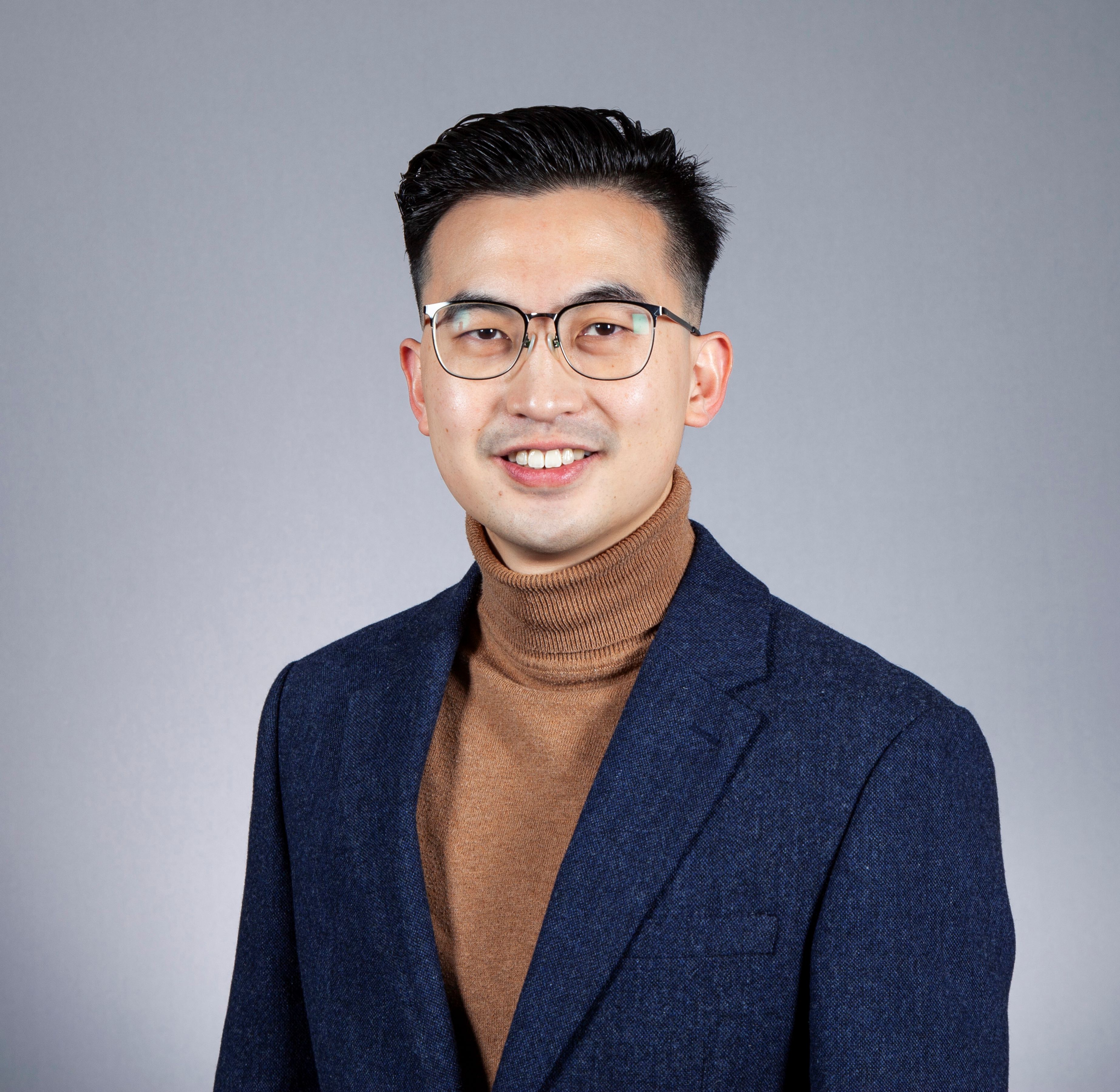 Benjamin Tan headshot wearing glasses and a polo neck