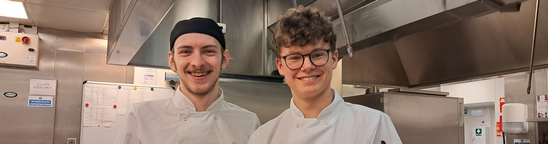 Two people in a kitchen wearing chef uniforms