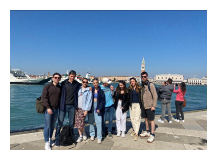 A group of friends in front of a body of water, with boats in the background