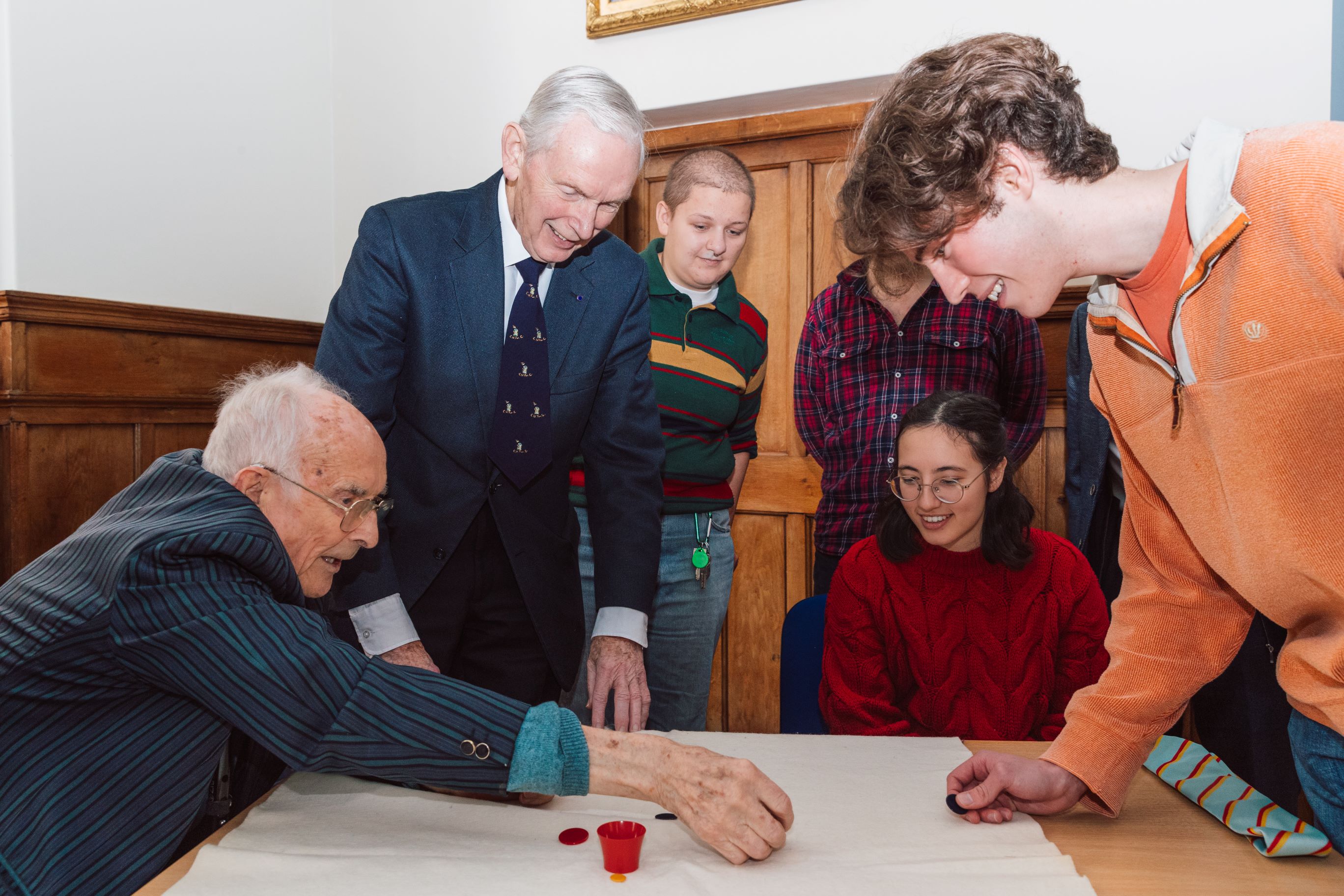 People ground around a table playing tiddlywinks