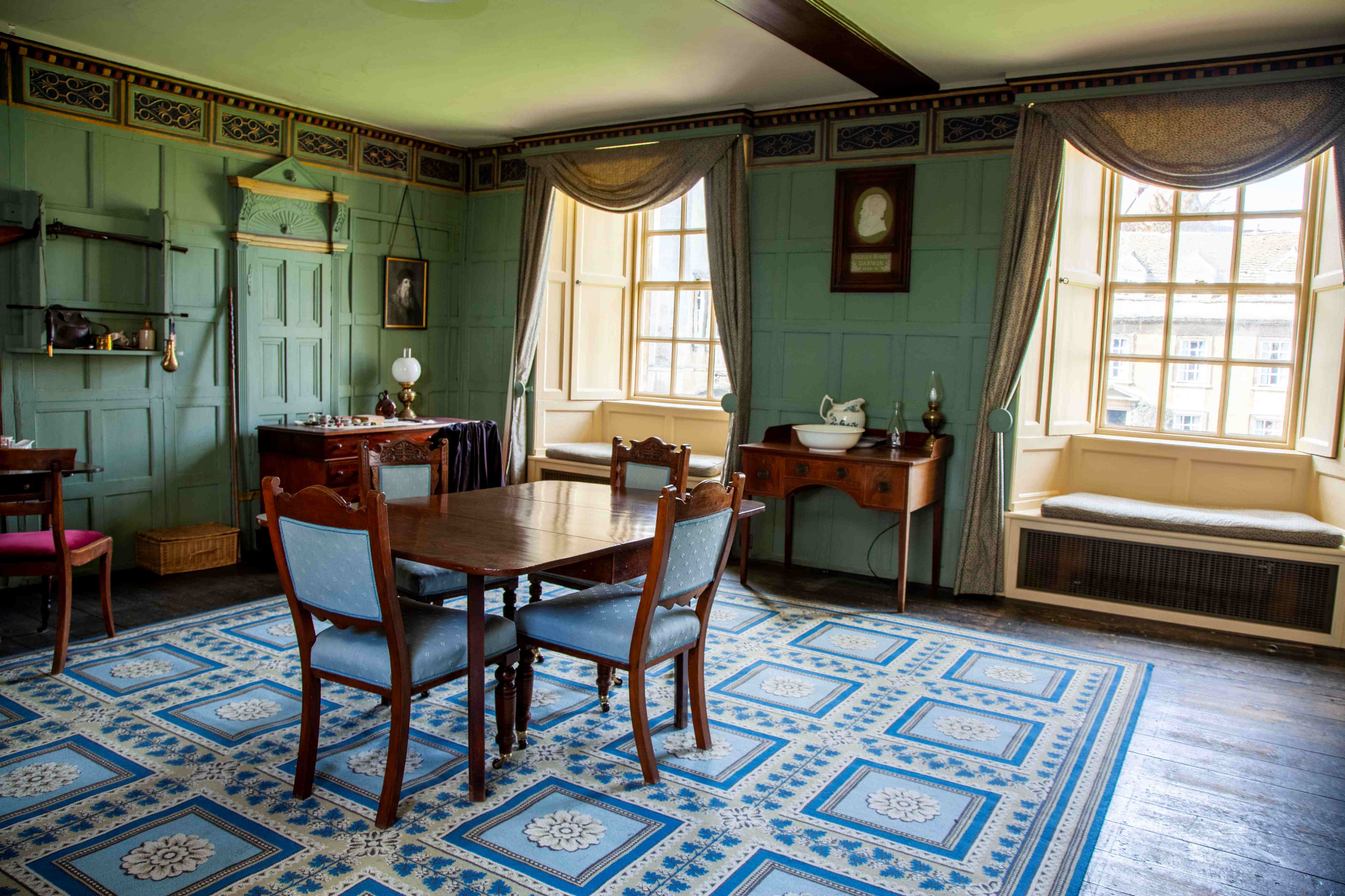 Interior of room with two sash windows, table and chairs in foreground