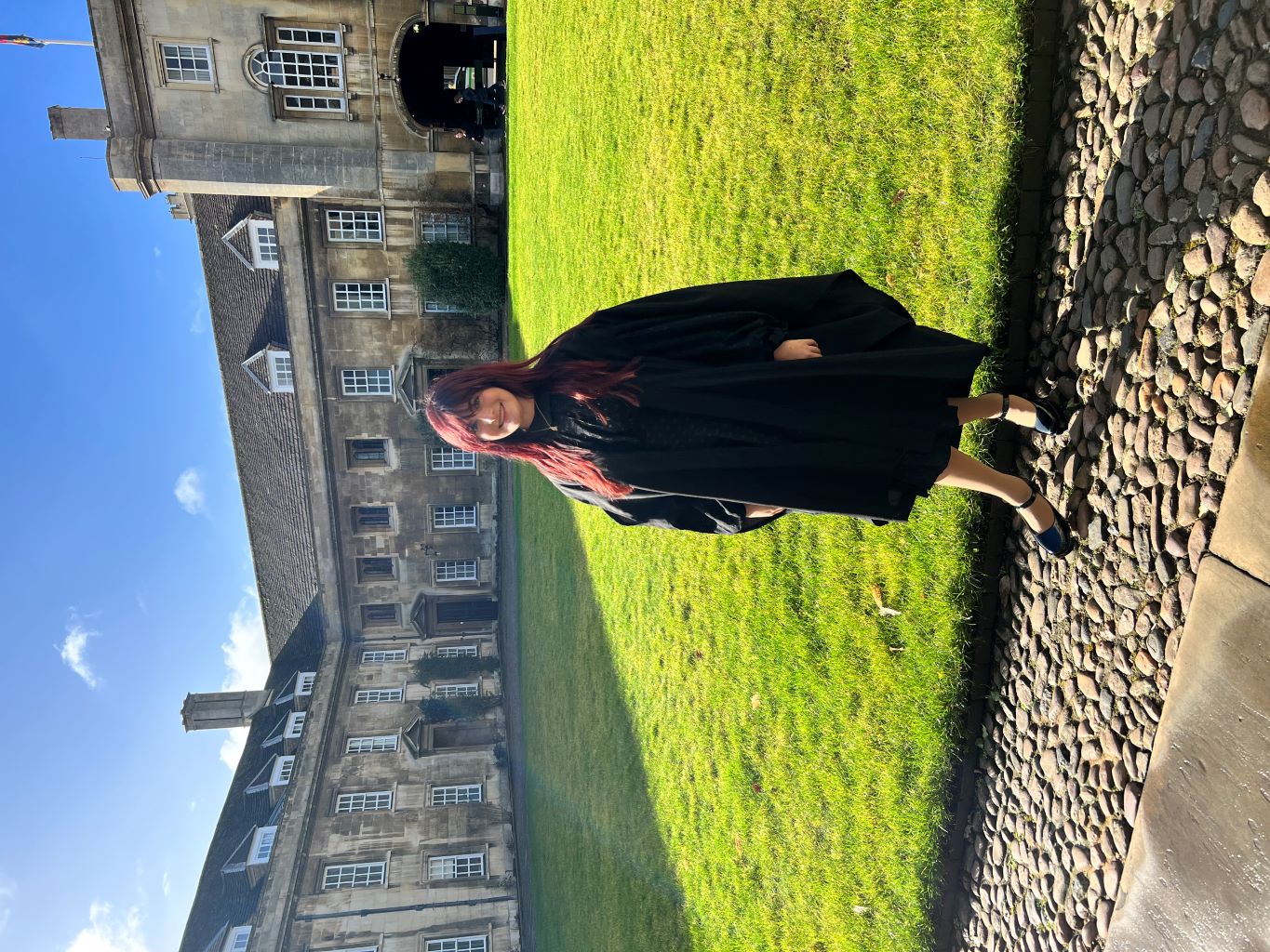 Figure in front of old buildings and grass