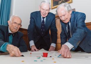 Three people play with and pot and tiddlywinks