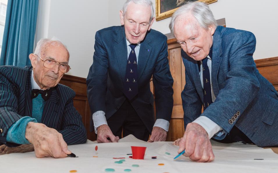 Three people play with and pot and tiddlywinks