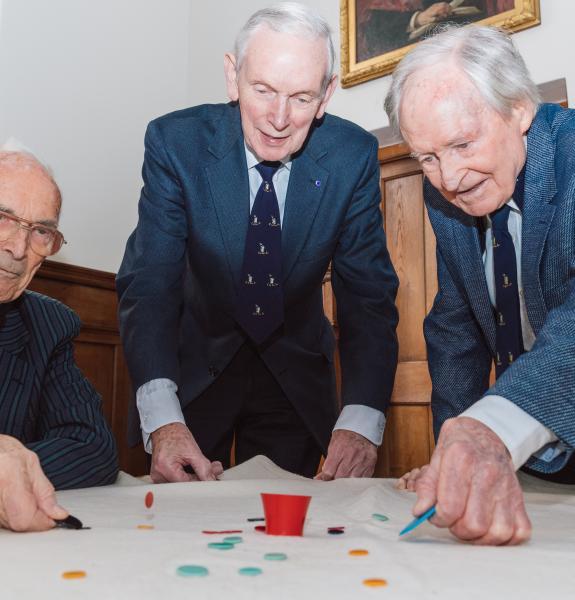 Three people play with and pot and tiddlywinks