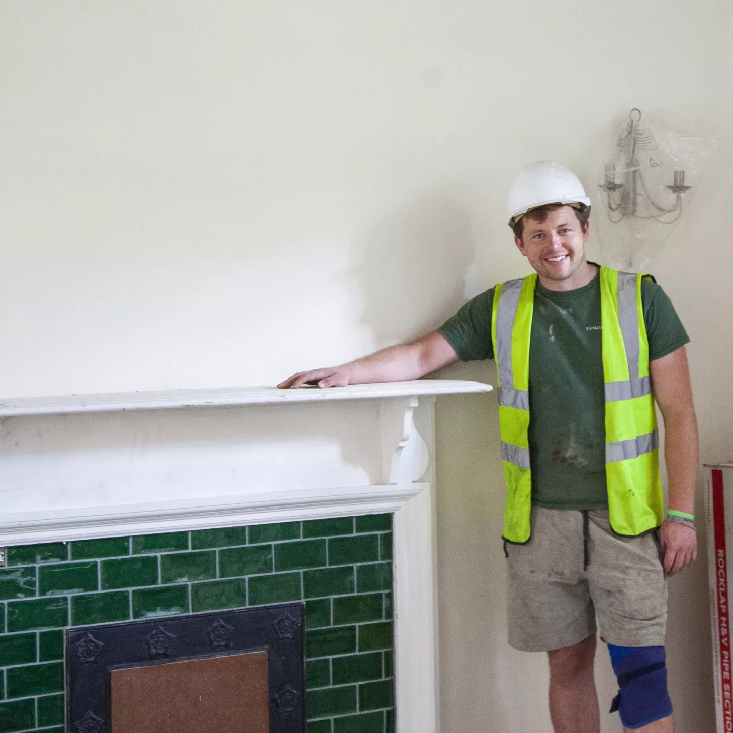 Person wearing a hard hat by a fireplace