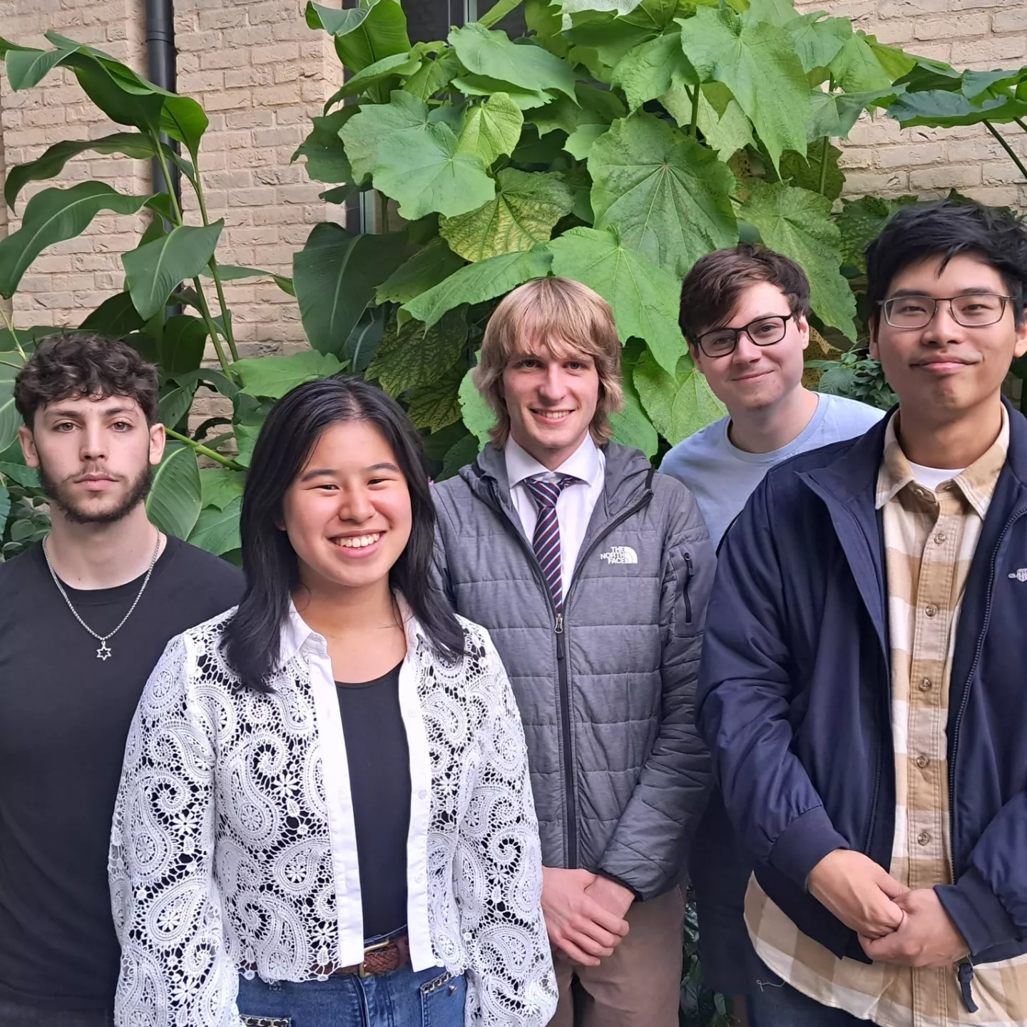 Group of five people in front of large outdoor plant