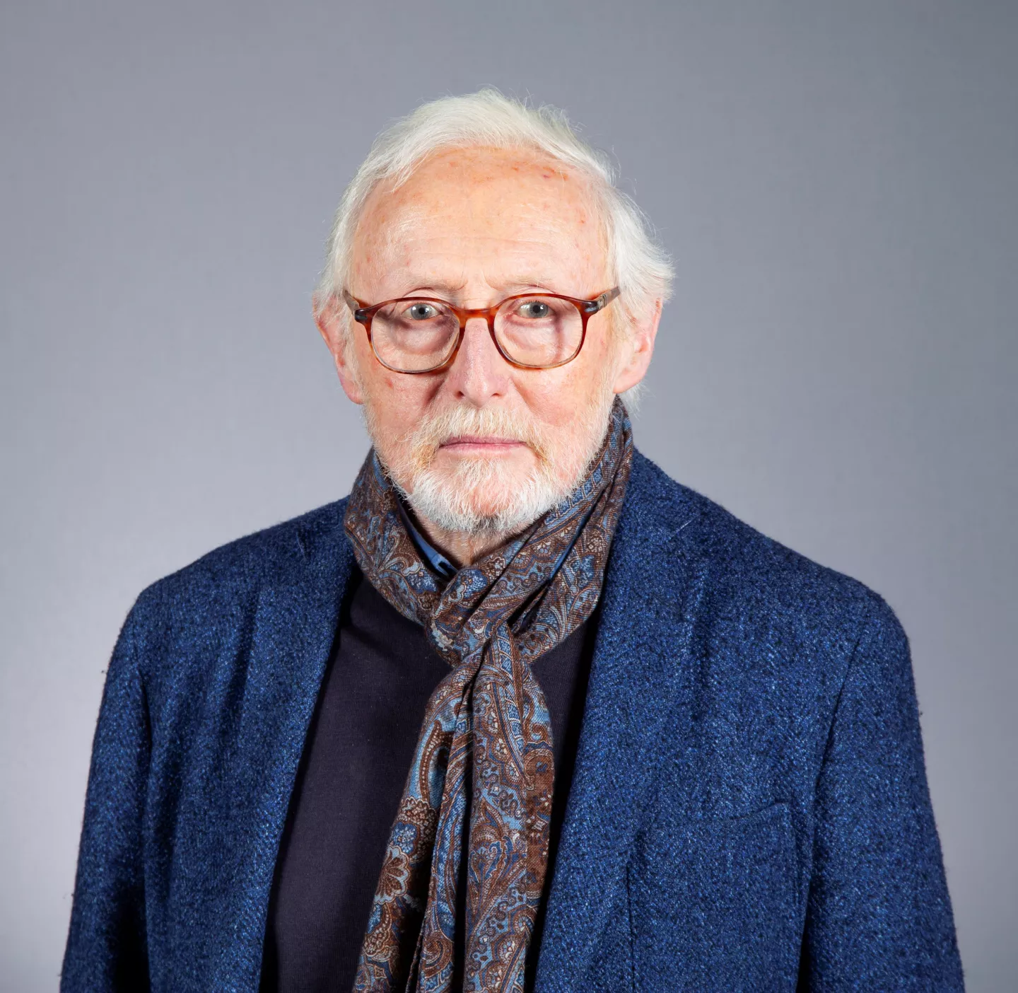 Bearded person wearing glasses and a scarf