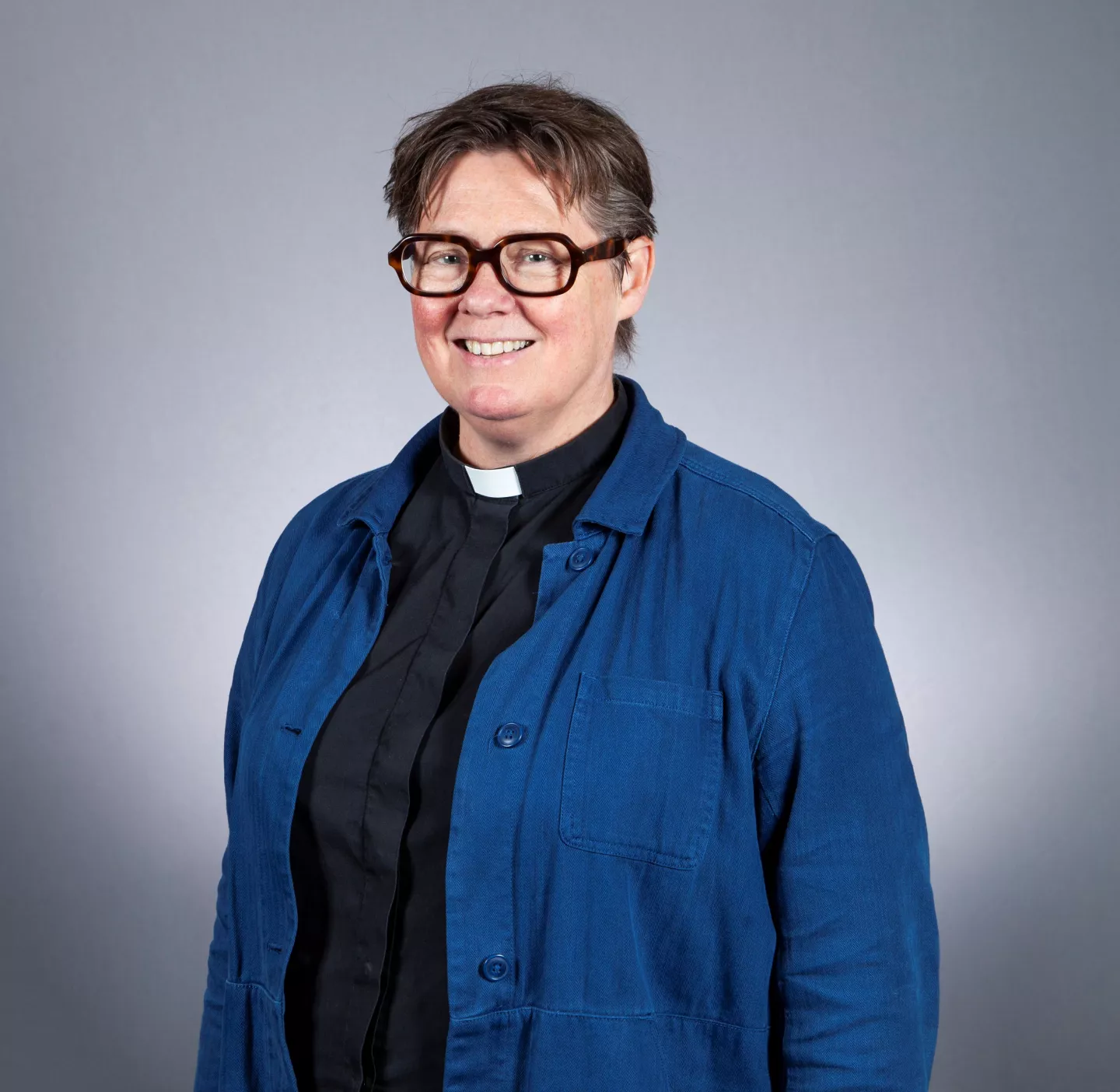 Smiling person with glasses and clerical collar